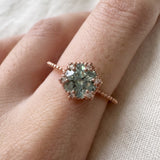 Rose gold mint green moissanite floral halo ring worn on a hand