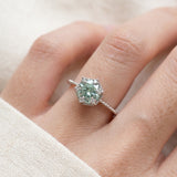 Silver mint green moissanite floral halo ring worn on a hand