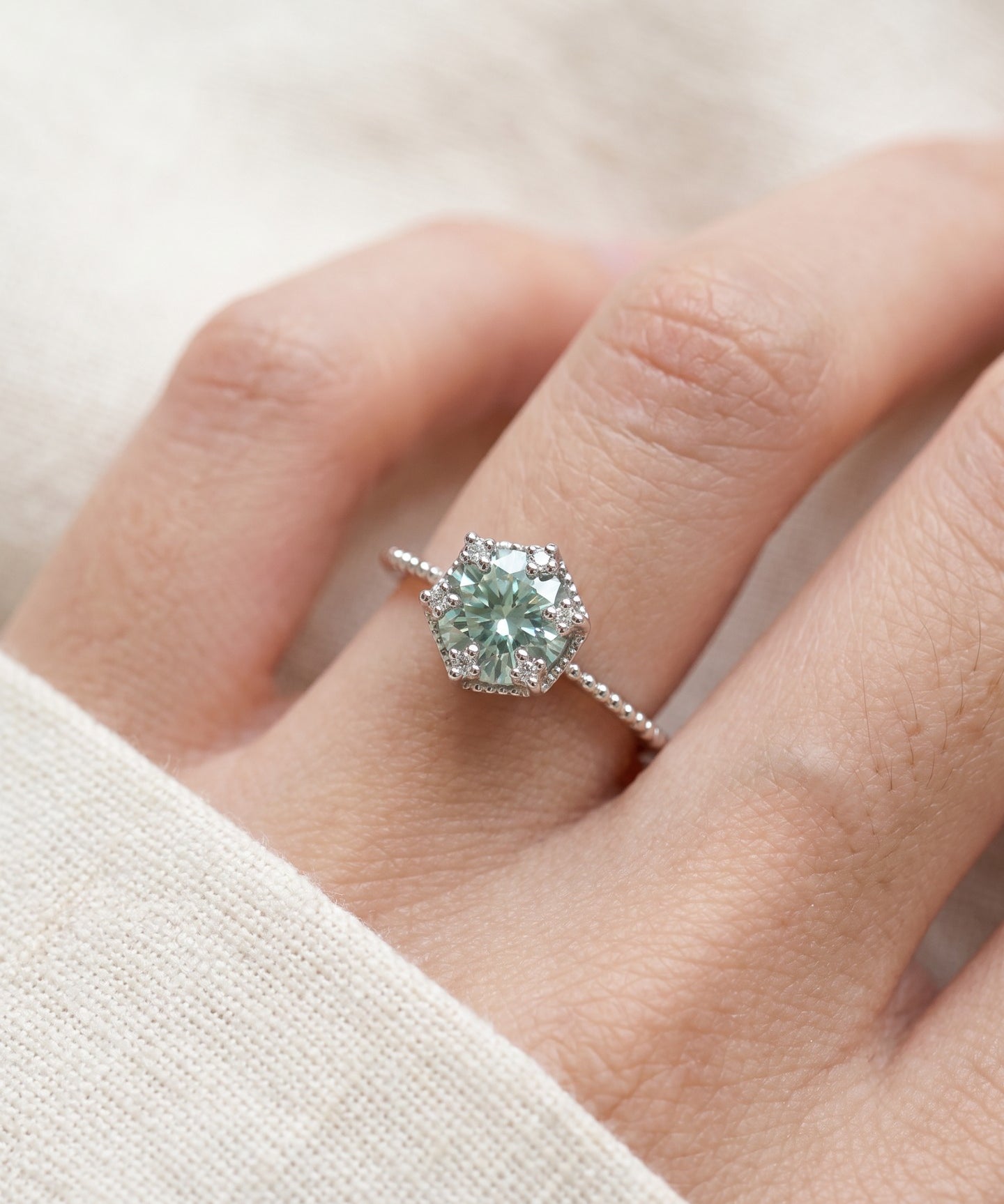 Silver mint green moissanite floral halo ring worn on a hand