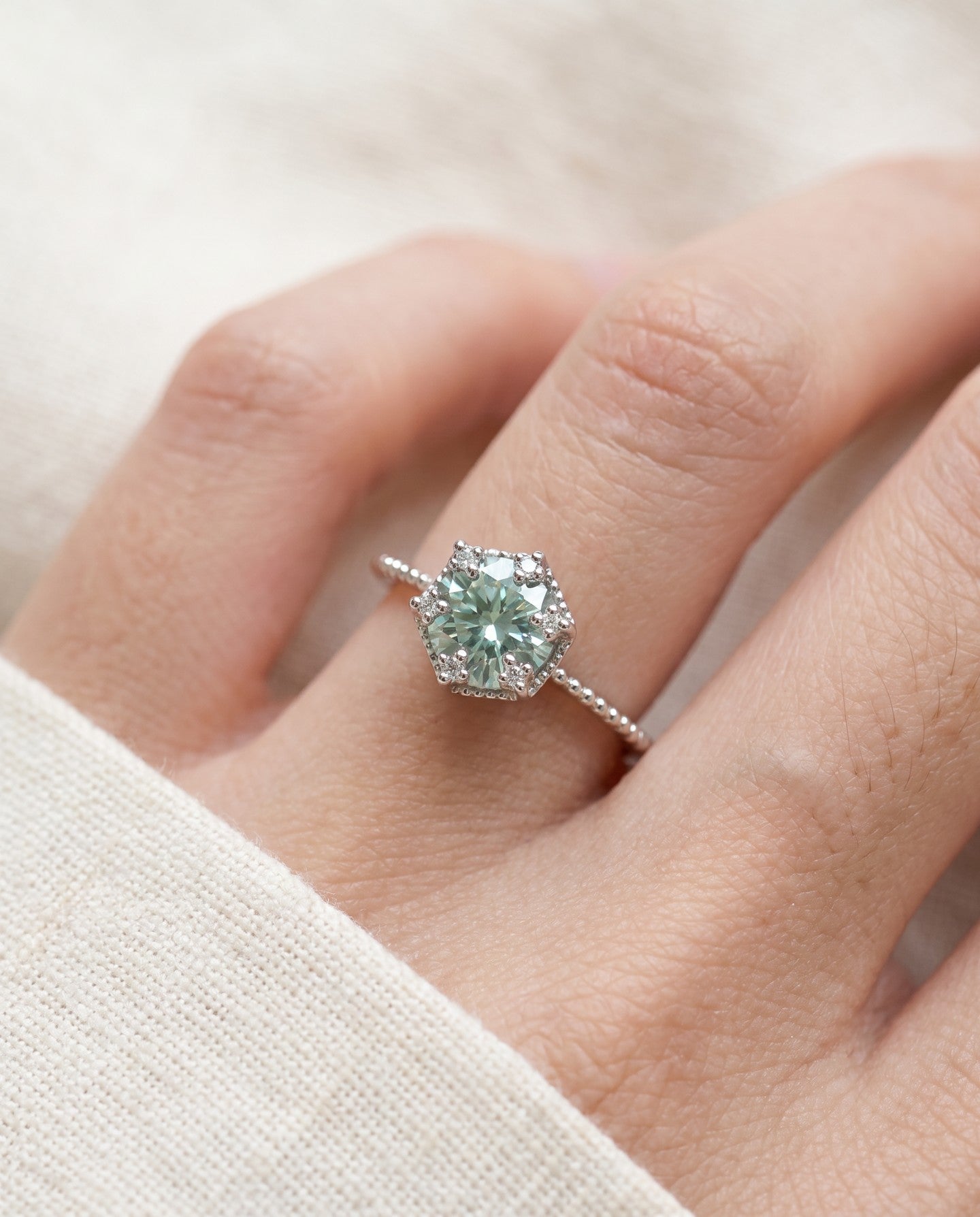 Silver mint green moissanite floral halo ring worn on a hand