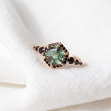 Nocturne Halo Hexagon Ring in rose gold, green lab-grown alexandrite with black CZ halo, resting on linen