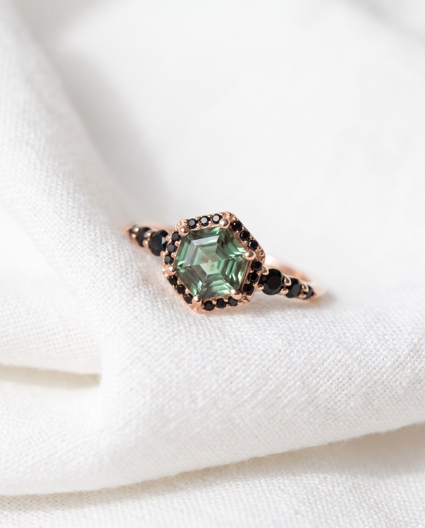 Nocturne Halo Hexagon Ring in rose gold, green lab-grown alexandrite with black CZ halo, resting on linen