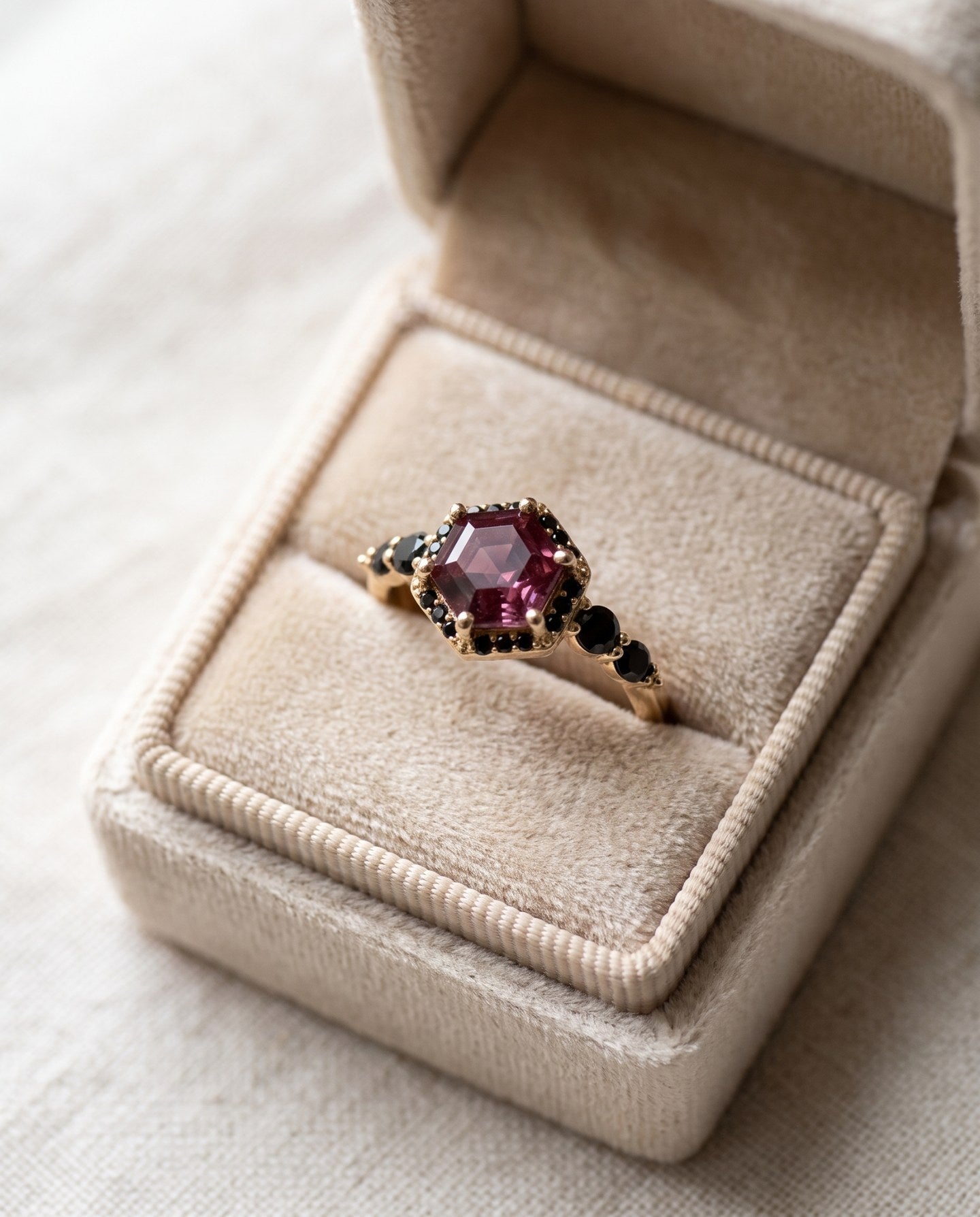 Nocturne Halo Hexagon Ring in yellow gold resting in a ring box, lab-grown alexandrite showing raspberry-pink tones with black CZ accents