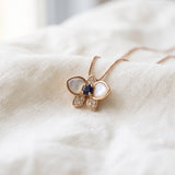Orchid Bloom Mother of Pearl Necklace in rose gold with iridescent wings and purple spinel centre on a soft ivory background