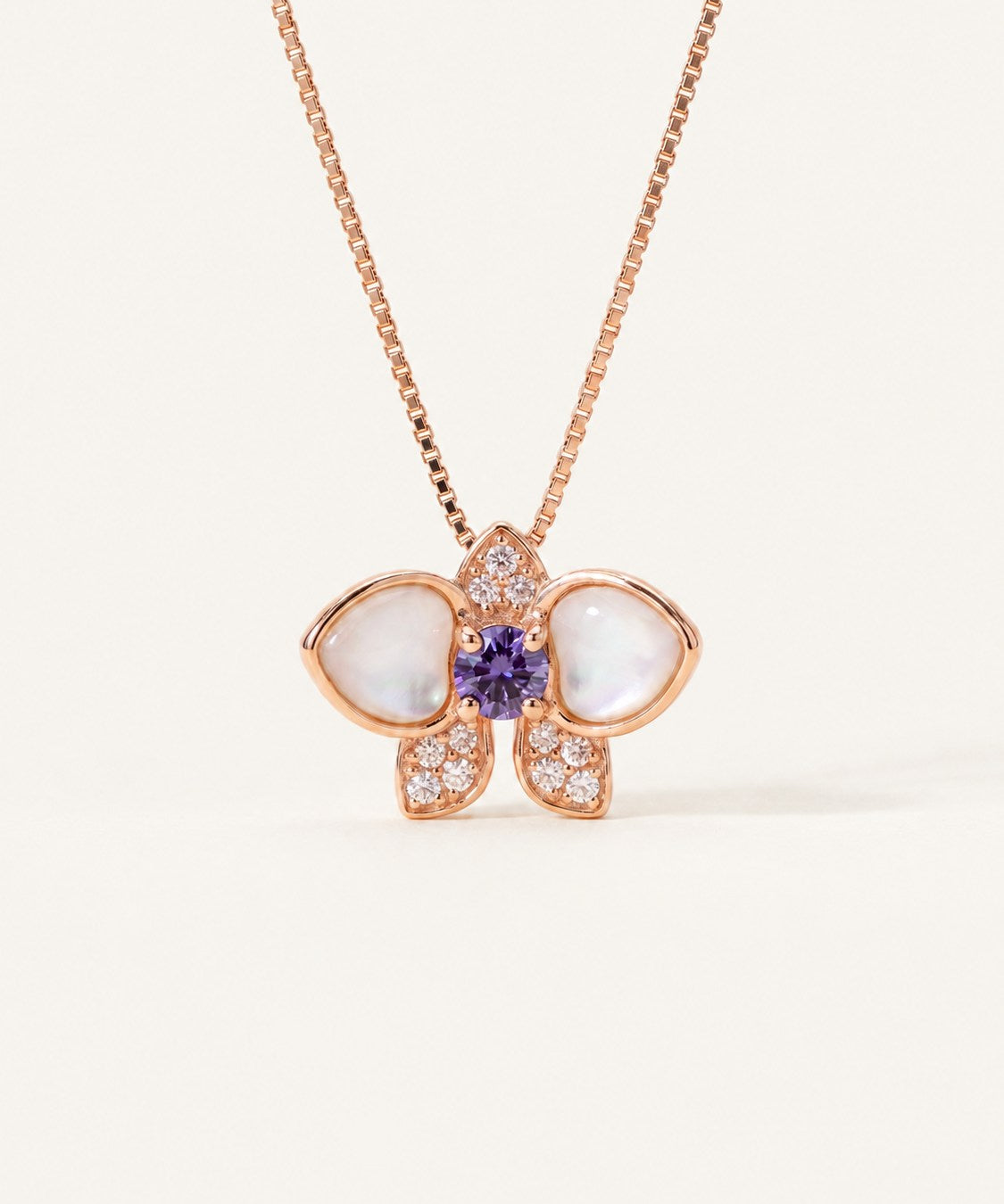 Orchid Bloom Mother of Pearl Necklace in rose gold with iridescent wings and purple spinel centre on a soft ivory background