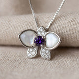 Orchid Bloom Mother of Pearl Necklace in silver with iridescent wings and purple spinel centre on a soft ivory background