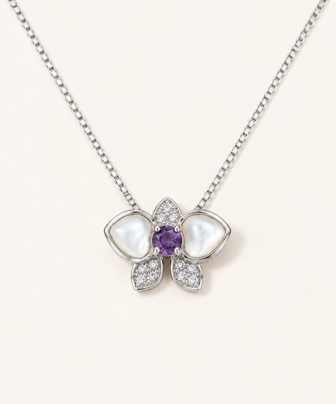 Orchid Bloom Mother of Pearl Necklace in silver with iridescent wings and purple spinel centre on a soft ivory background
