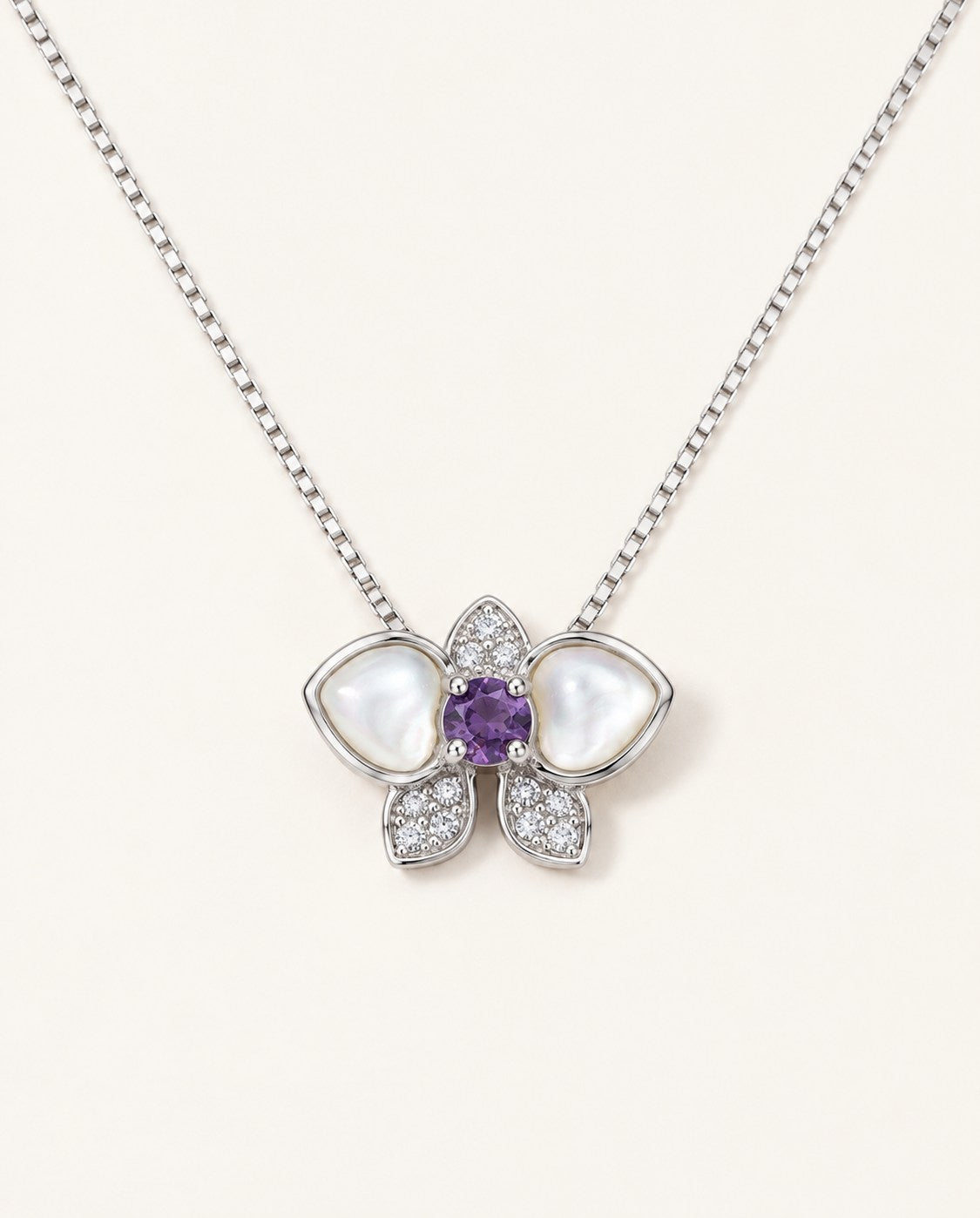 Orchid Bloom Mother of Pearl Necklace in silver with iridescent wings and purple spinel centre on a soft ivory background