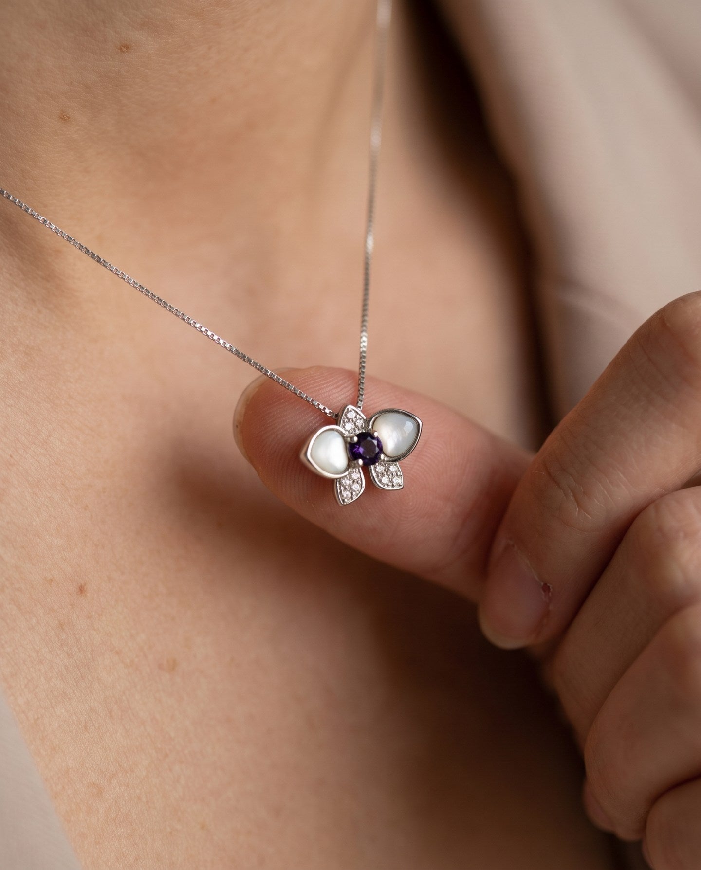 Orchid Bloom Mother of Pearl Necklace in silver with iridescent wings and purple spinel centre worn at the collarbone