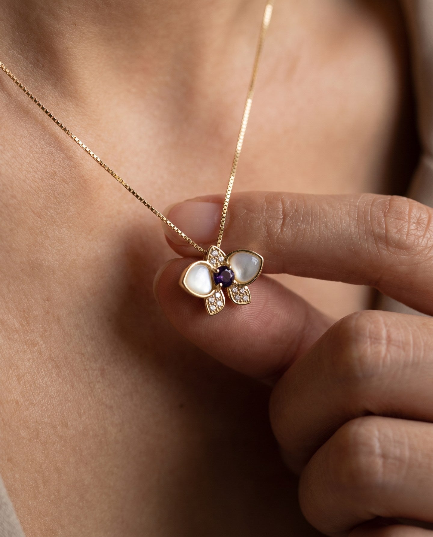 Orchid Bloom Mother of Pearl Necklace in yellow gold with iridescent wings and purple spinel centre worn at the collarbone