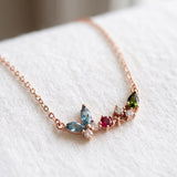 Papillon and Blossom butterfly necklace in rose gold with teal apatite, rhodolite garnet and chrome diopside on a neutral ivory background