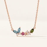 Papillon and Blossom butterfly necklace in rose gold with teal apatite, rhodolite garnet and chrome diopside on a neutral ivory background
