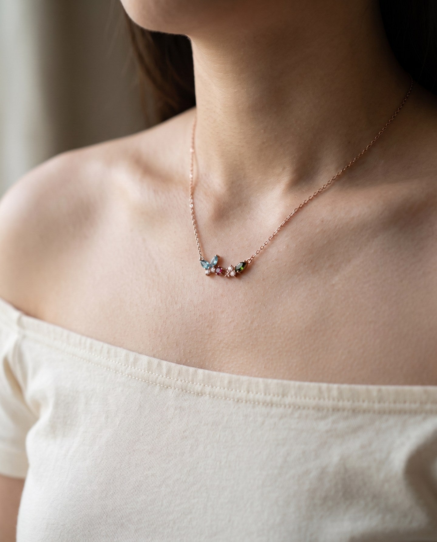 Papillon and Blossom butterfly necklace in rose gold with teal apatite, rhodolite garnet and chrome diopside worn at the collarbone