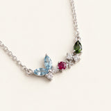 Papillon and Blossom butterfly necklace in silver with teal apatite, rhodolite garnet and chrome diopside on a neutral ivory background