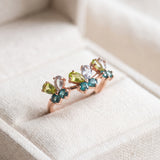 Papillon Butterfly Meadow Ring in rose gold with peridot and blue topaz butterflies on a light neutral background