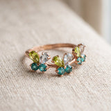 Papillon Butterfly Meadow Ring in rose gold with peridot and blue topaz butterflies on a light neutral background