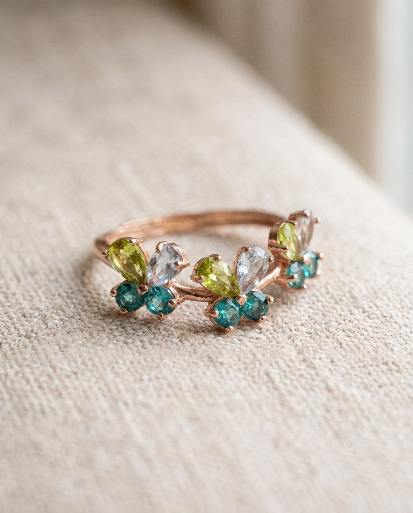 Papillon Butterfly Meadow Ring in rose gold with peridot and blue topaz butterflies on a light neutral background