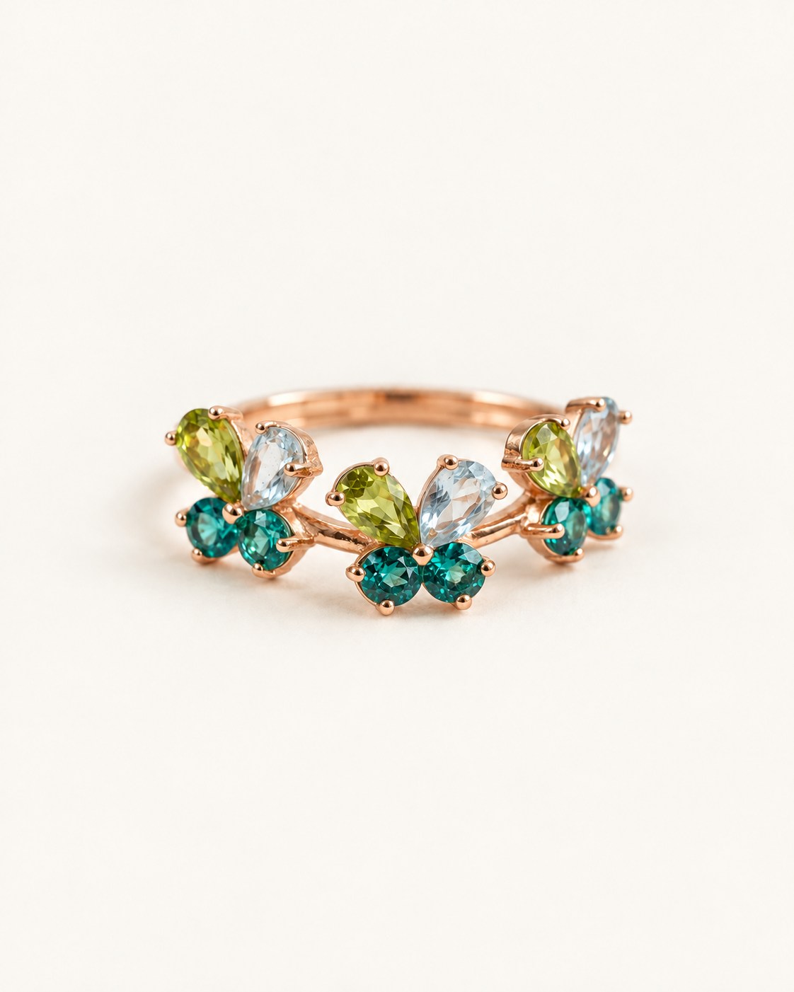 Papillon Butterfly Meadow Ring in rose gold with peridot and blue topaz butterflies on a light neutral background