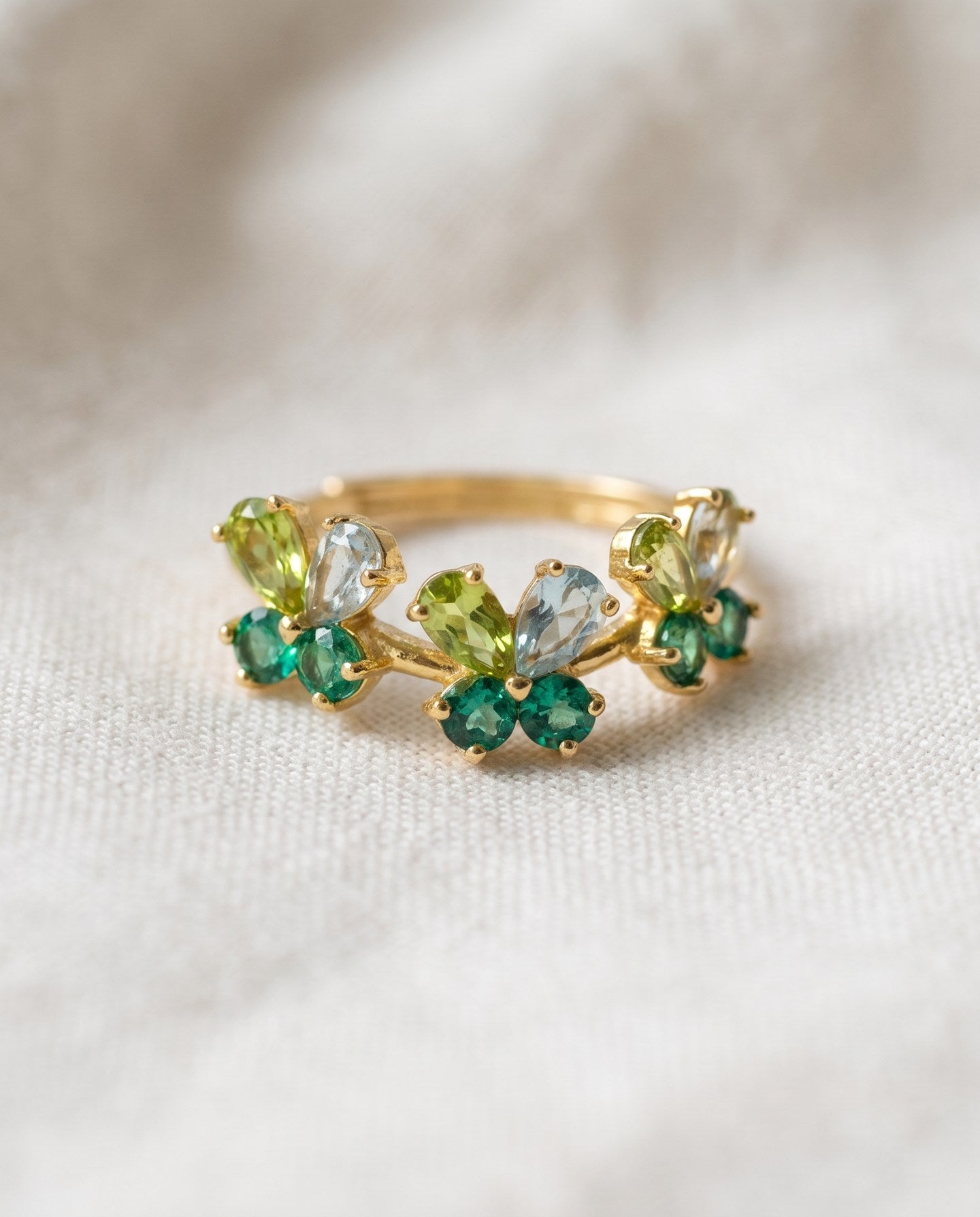 Papillon Butterfly Meadow Ring in yellow gold with peridot and blue topaz butterflies on a light neutral background