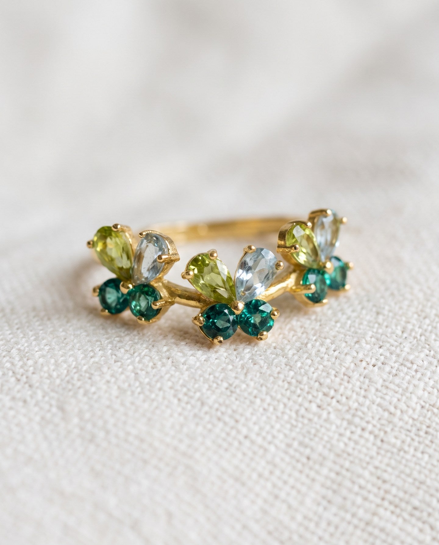 Papillon Butterfly Meadow Ring in yellow gold with peridot and blue topaz butterflies on a light neutral background