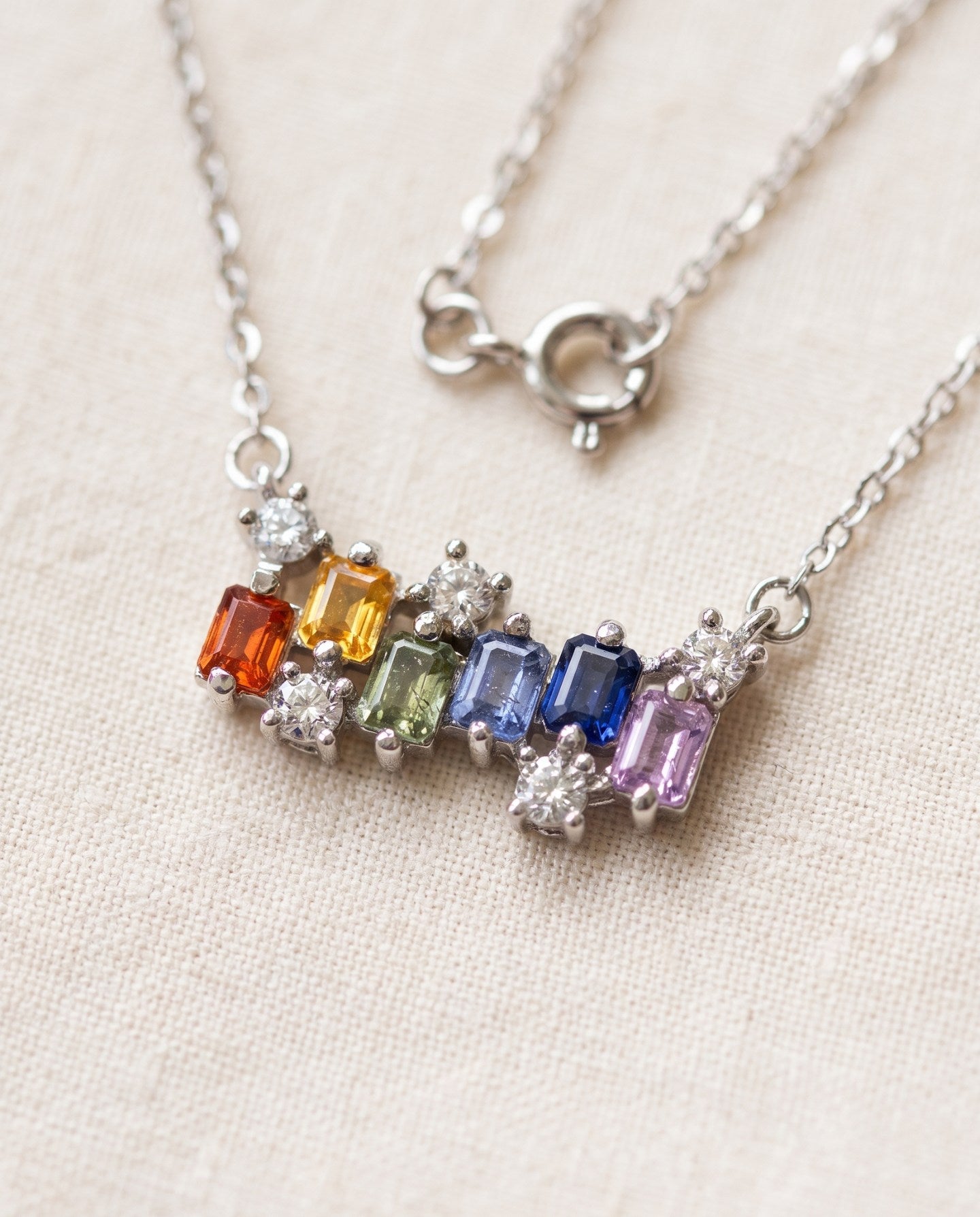 Prism Baguette Rainbow Sapphire Necklace in silver with six multicolour natural sapphires on a neutral ivory background