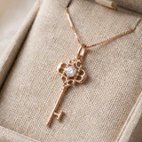 Memoir Grey Moissanite Key Necklace in rose gold, styled on neutral fabric