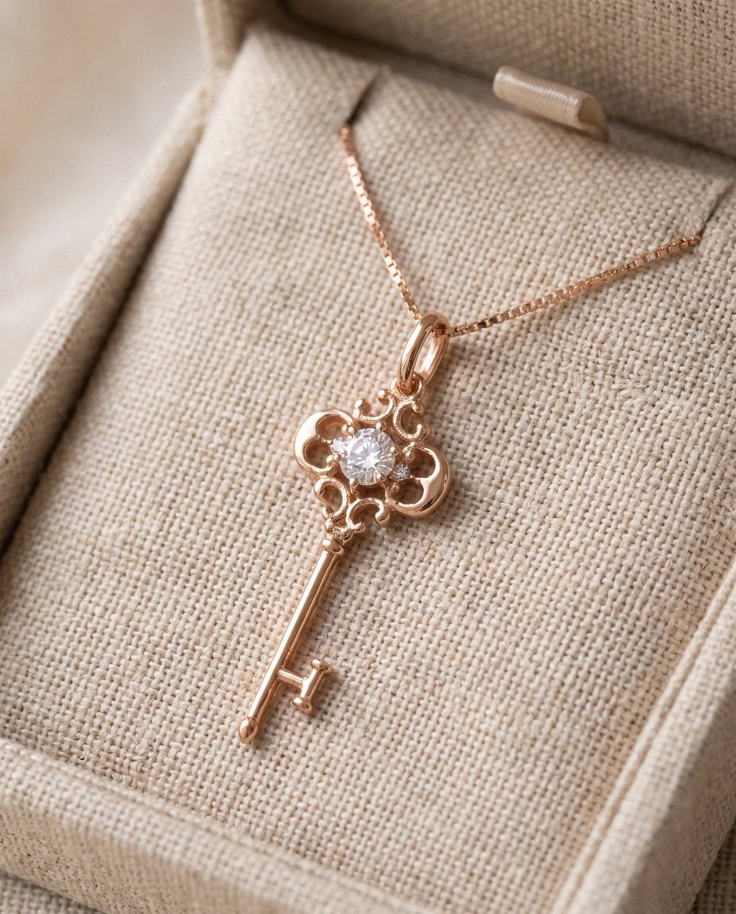 Memoir Grey Moissanite Key Necklace in rose gold, styled on neutral fabric
