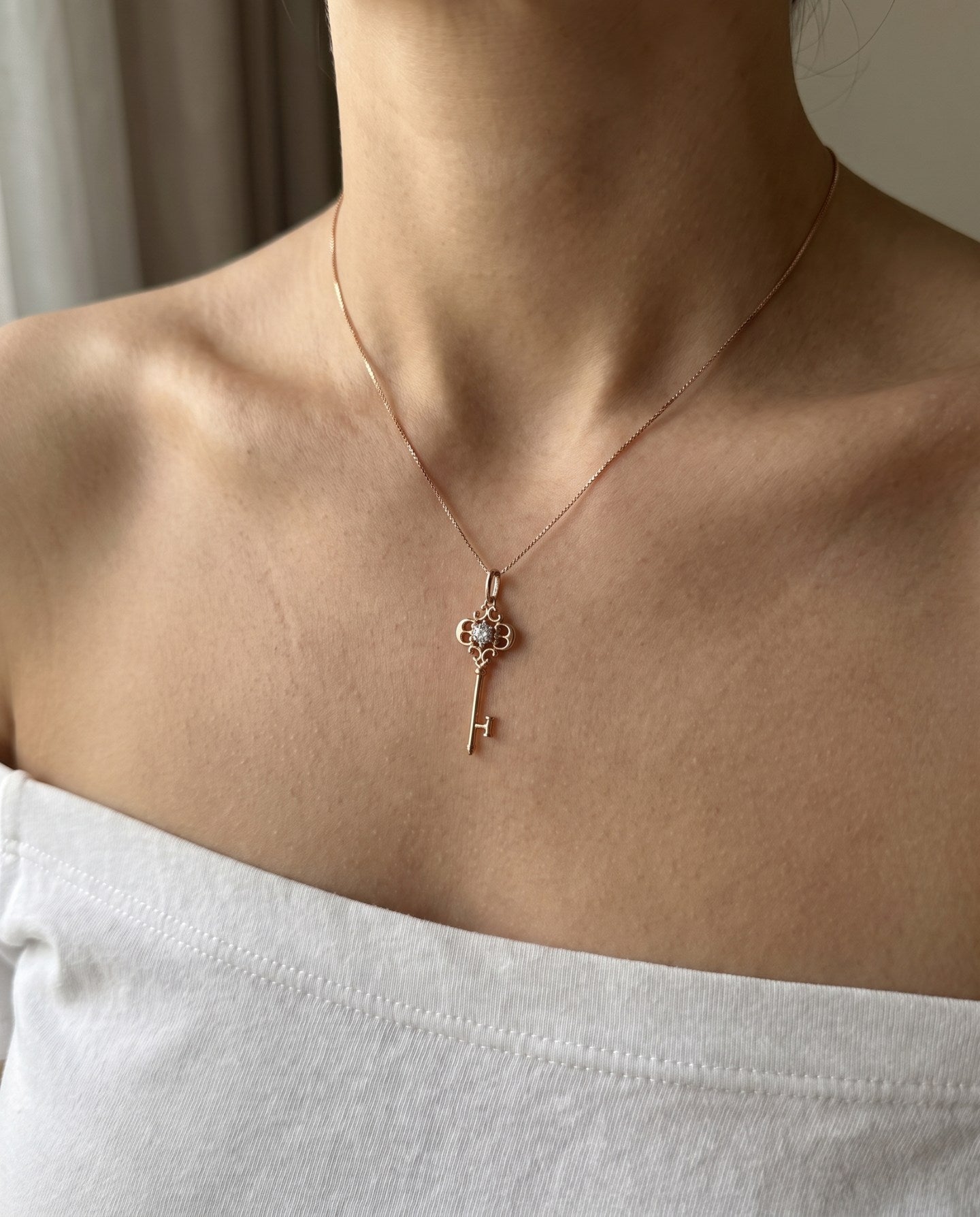 Memoir Grey Moissanite Key Necklace in rose gold, worn on a delicate chain in natural light