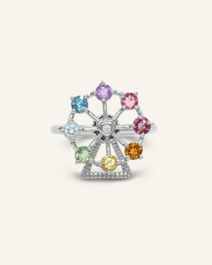 Close-up of the Spinning Ferris Wheel Ring with natural gemstones, resting on a warm linen background