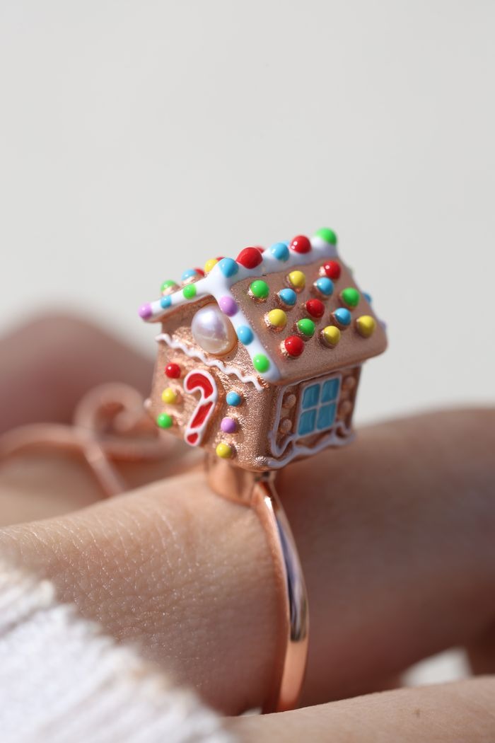 Spinning Gingerbread House Ring in rose gold, close-up worn on a hand, showing the candy roof and front door