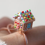 Spinning Gingerbread House Ring in rose gold, close-up worn on a hand, showing the candy roof and front door
