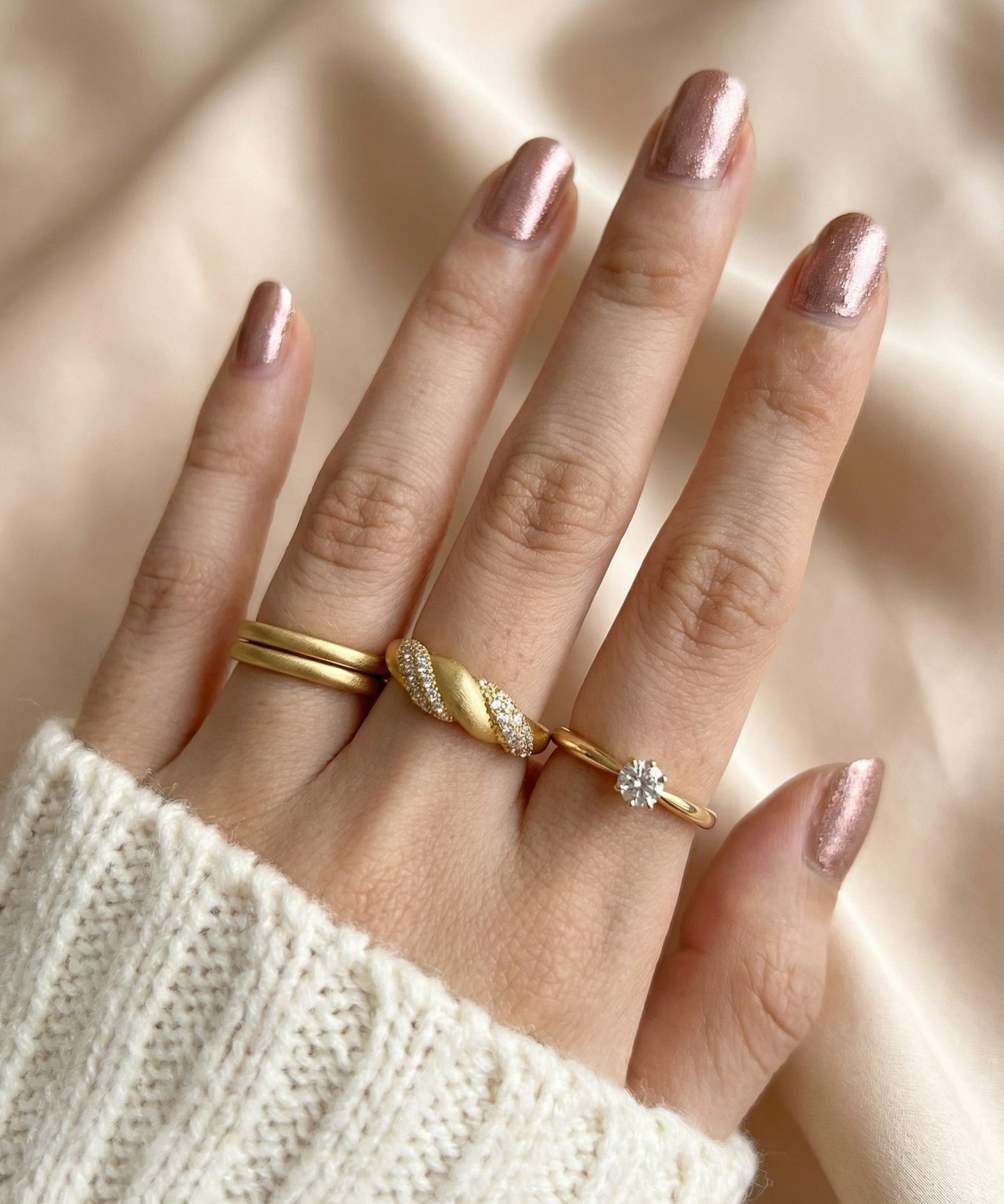 Sugar Sprinkled Croissant Ring in yellow gold, worn on a hand beside slim gold rings with an ivory knit sleeve