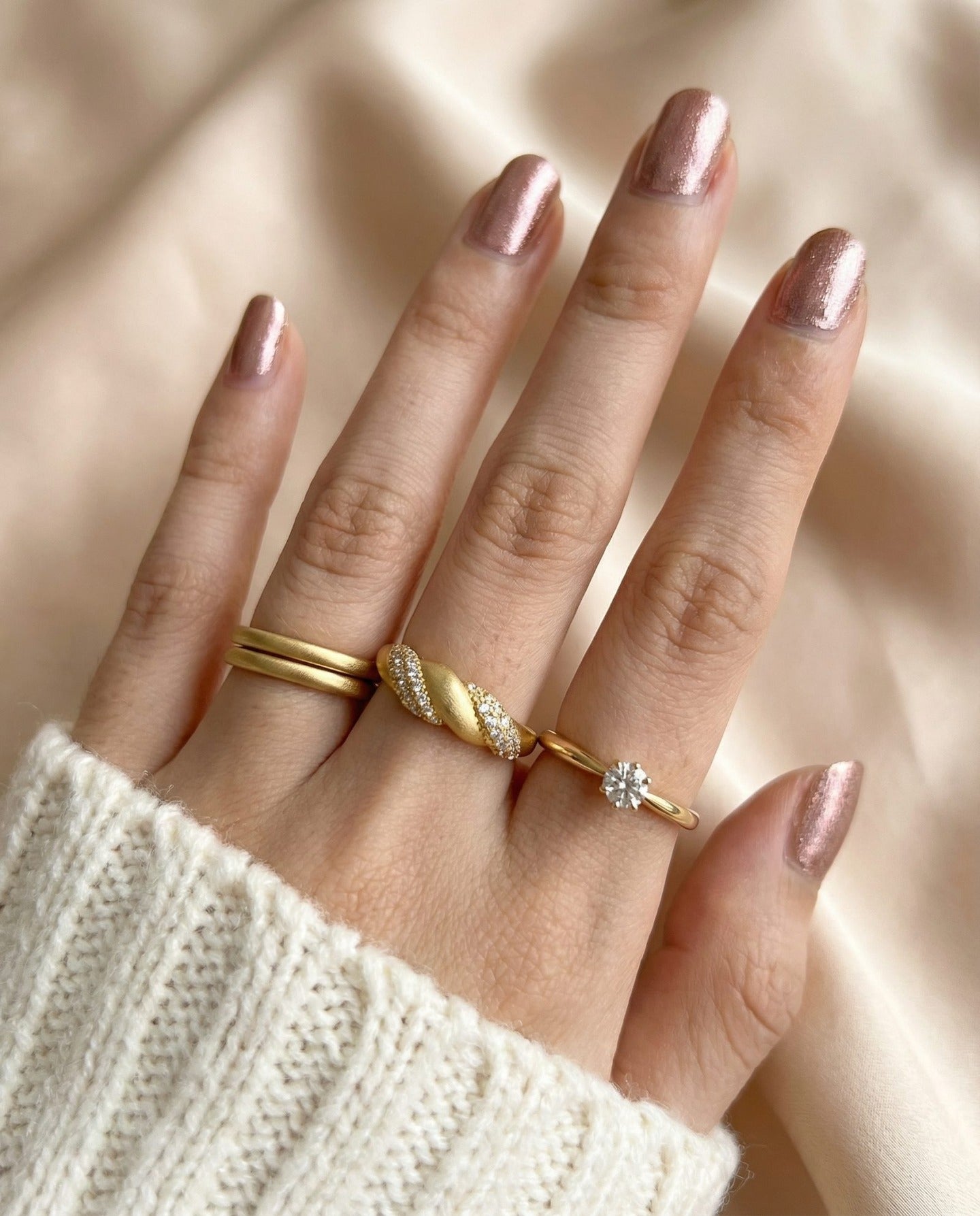 Sugar Sprinkled Croissant Ring in yellow gold, worn on a hand beside slim gold rings with an ivory knit sleeve